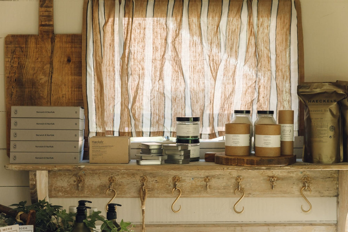 Shelf under the shed shop window with Haeckels seaweed bath products, Made by Coopers candles and bath salts, and old wooden boards